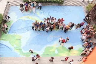 Photographie des bibliothécaires de la Caraïbe se tenant debout sur une fresque représentant les Caraïbes sur le parvis du Centre culturel de la FOKAL