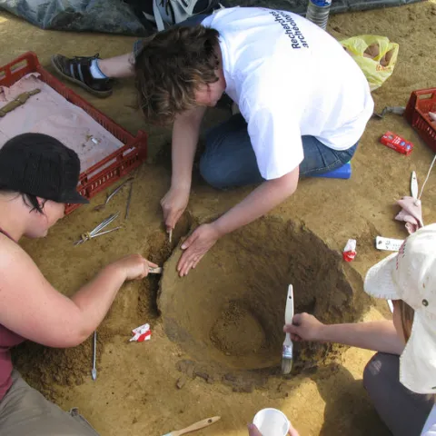 Photographie d'un groupe de trois personnes réalisant des fouilles